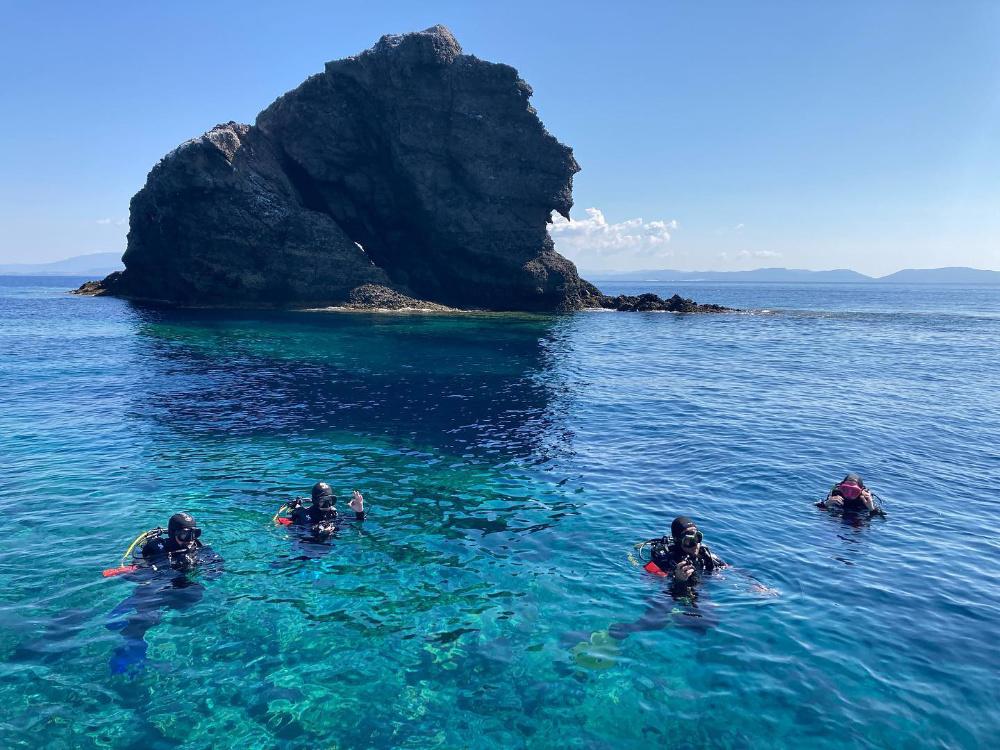 People learning diving in a sea with rocky island in the background
