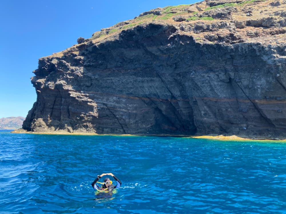 Diver showing signal with Sardinia shore in background