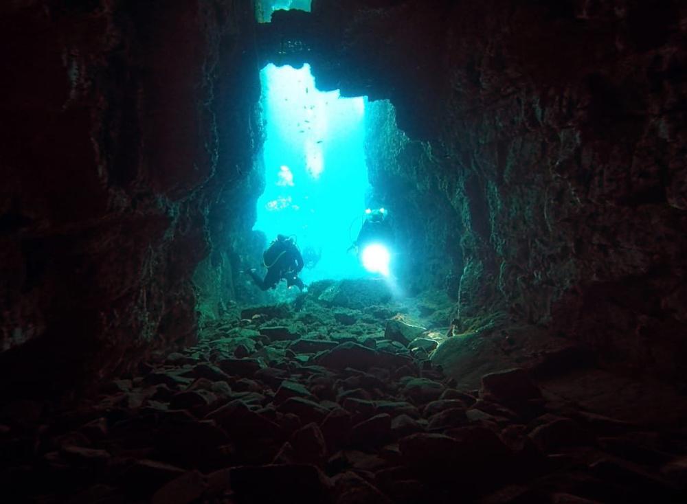 Two scuba divers with a torchlight in uderwater cave